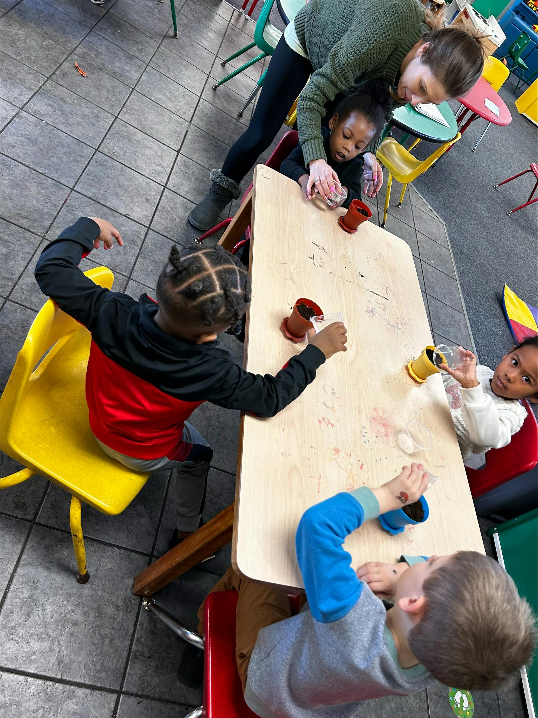 Adult and children at a table with small pots