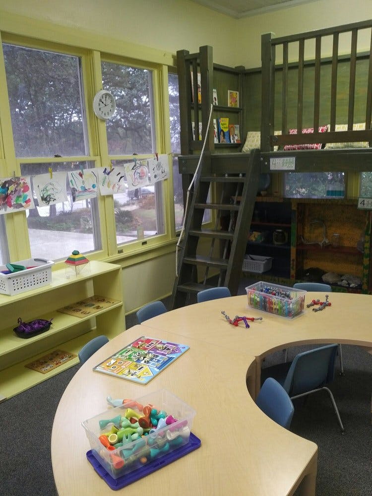 Classroom with a loft, windows, and a curved table with puzzles and toys