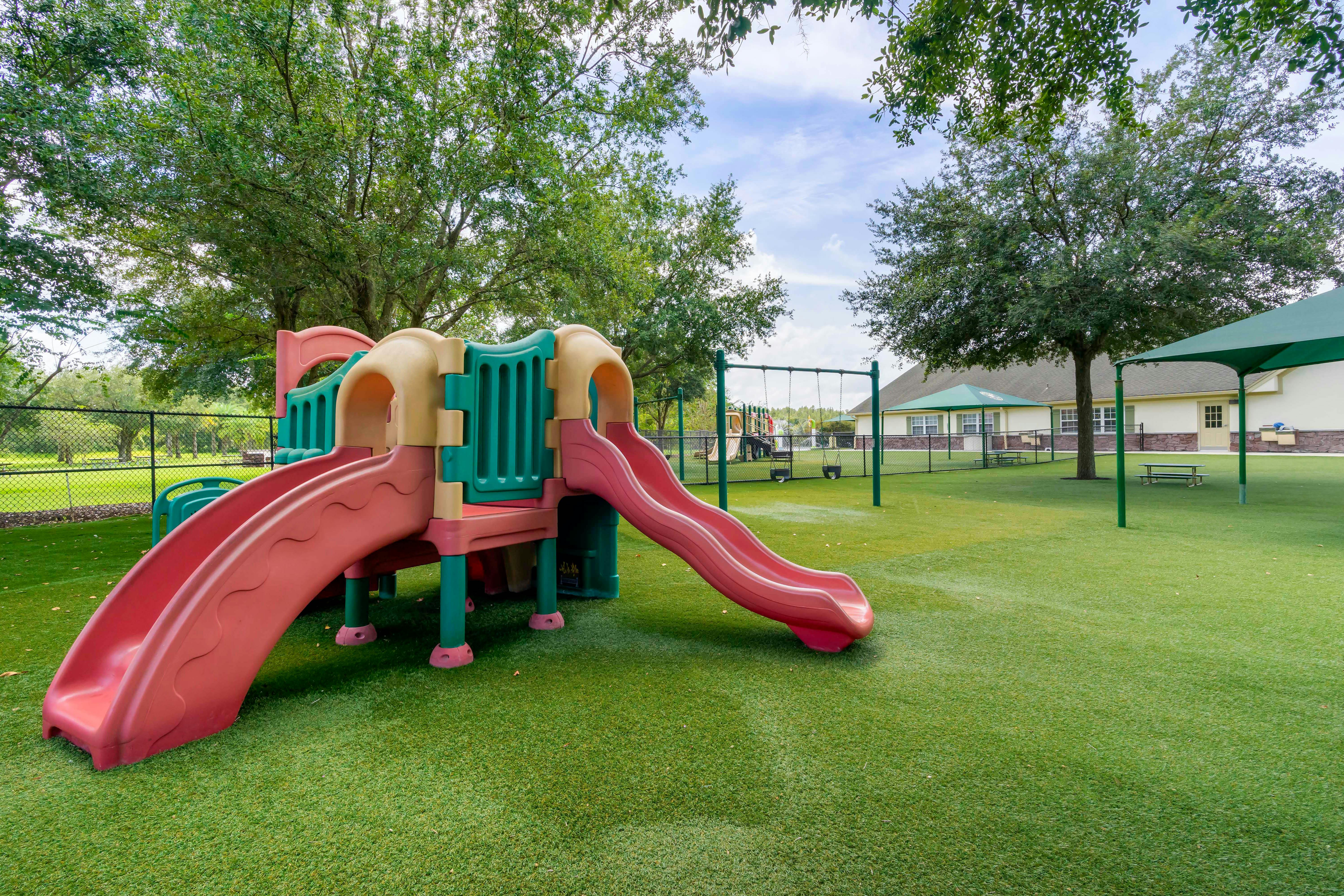 A playground with a large climbing structure, two slides, and a swing set