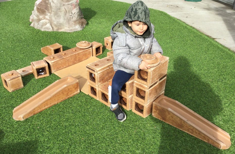 Child playing with large building blocks on artificial grass