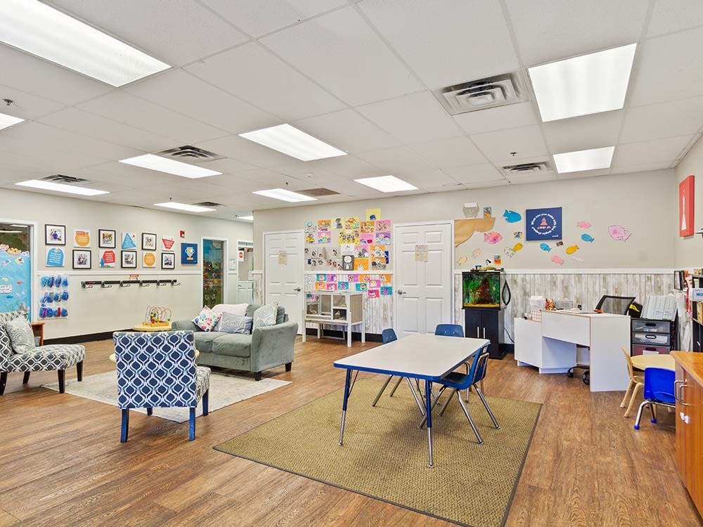 Spacious childcare classroom with tables, chairs, and play areas