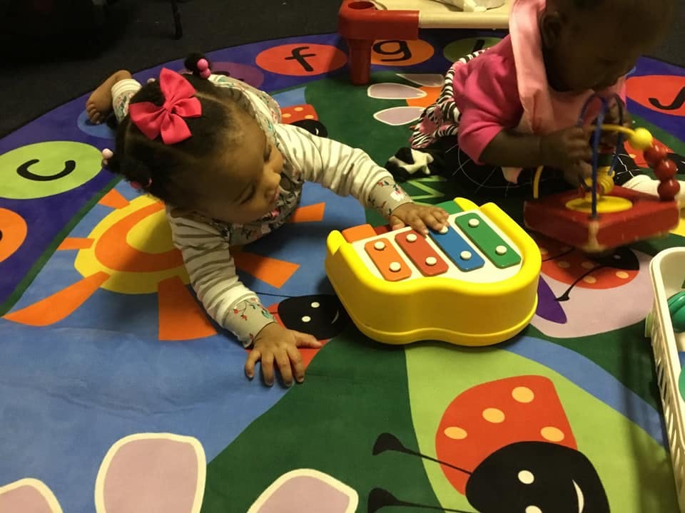 Two children playing with toys on a colorful rug