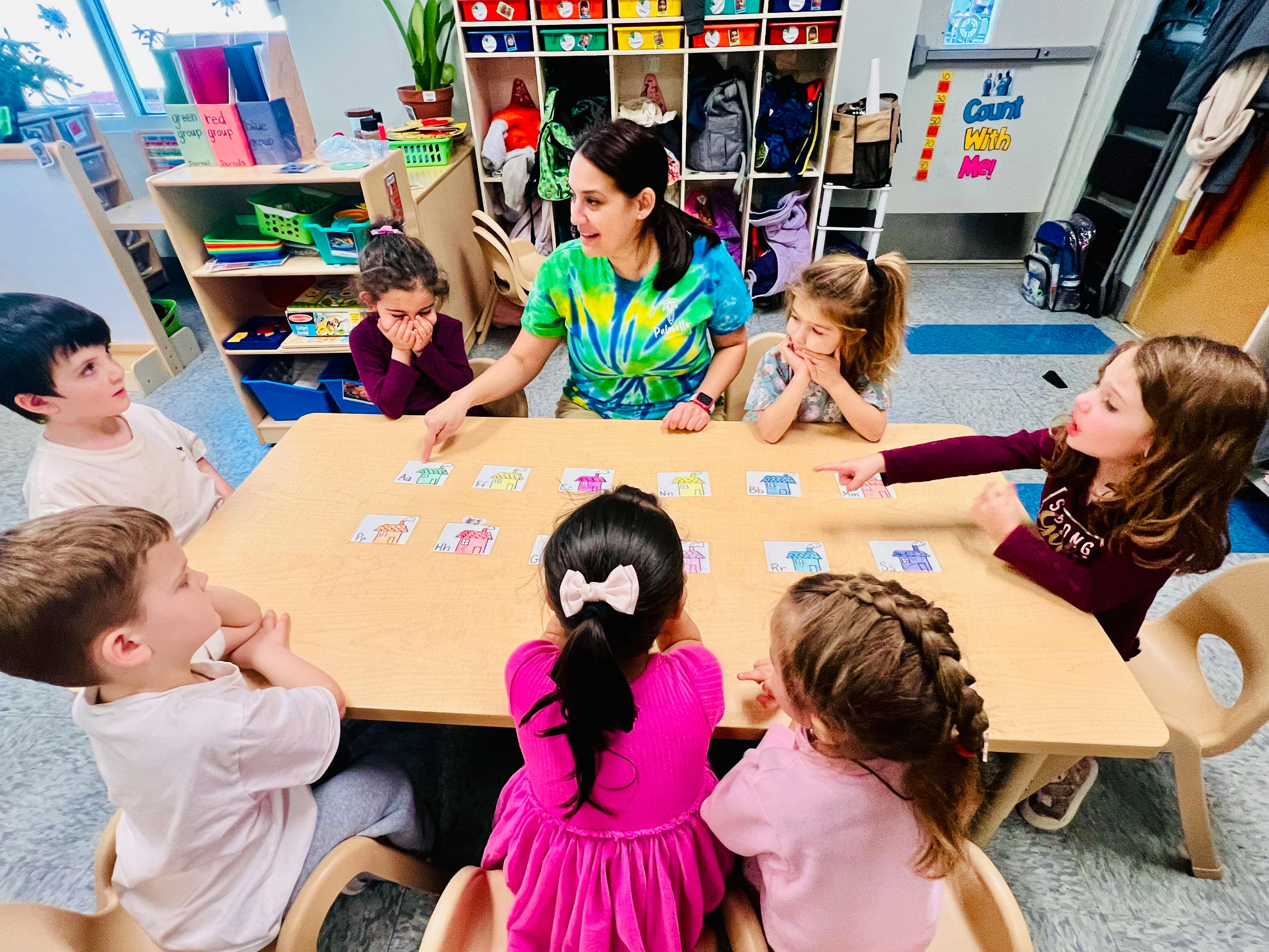 adult and children sitting around a table with cards on it in a classroom