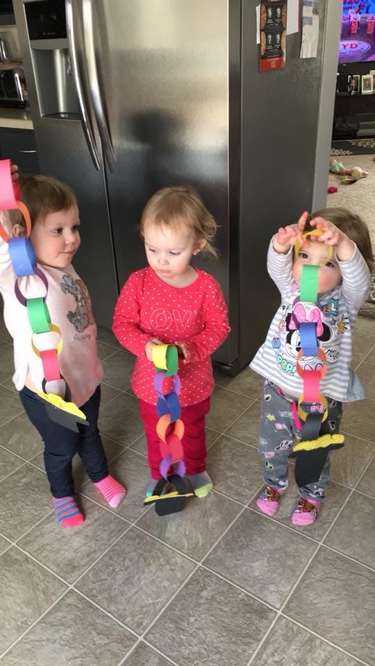 Three children holding colorful paper chains