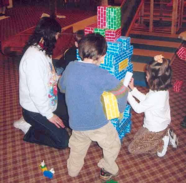 Adult and two children playing with large colorful blocks