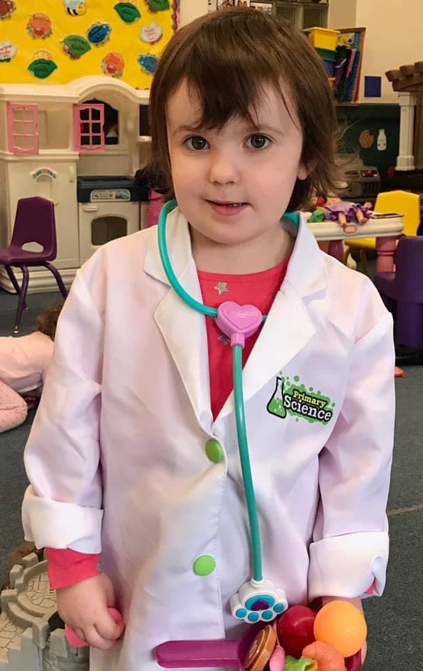 Child wearing a white lab coat and a toy stethoscope