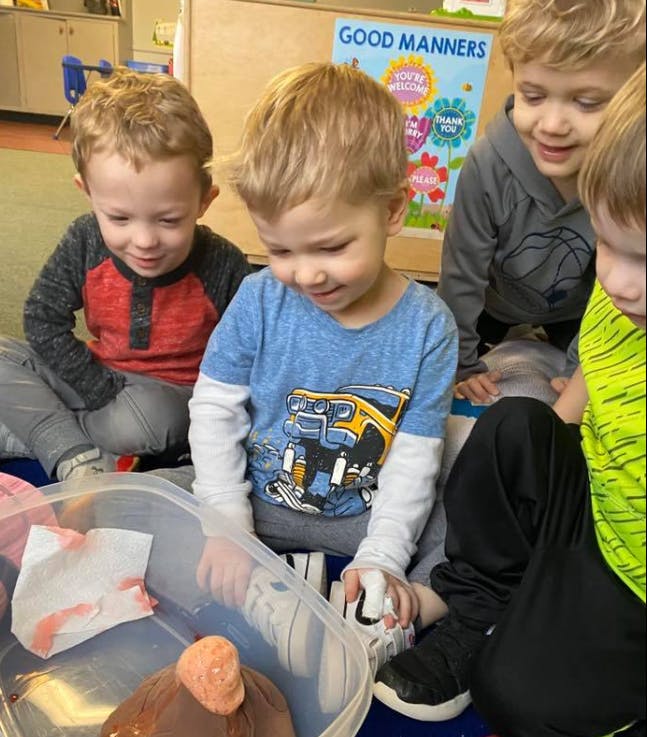 Children gathered around a container with a small volcano model