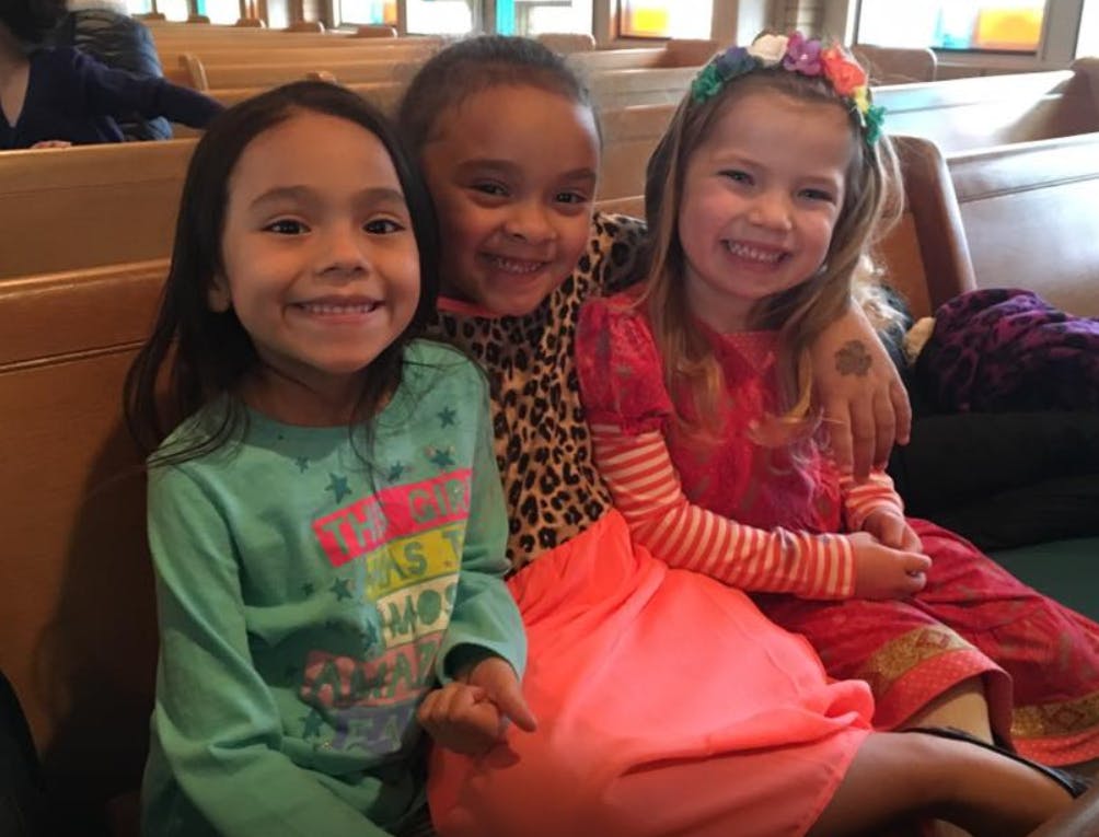 Three children sitting together, one with an arm around another
