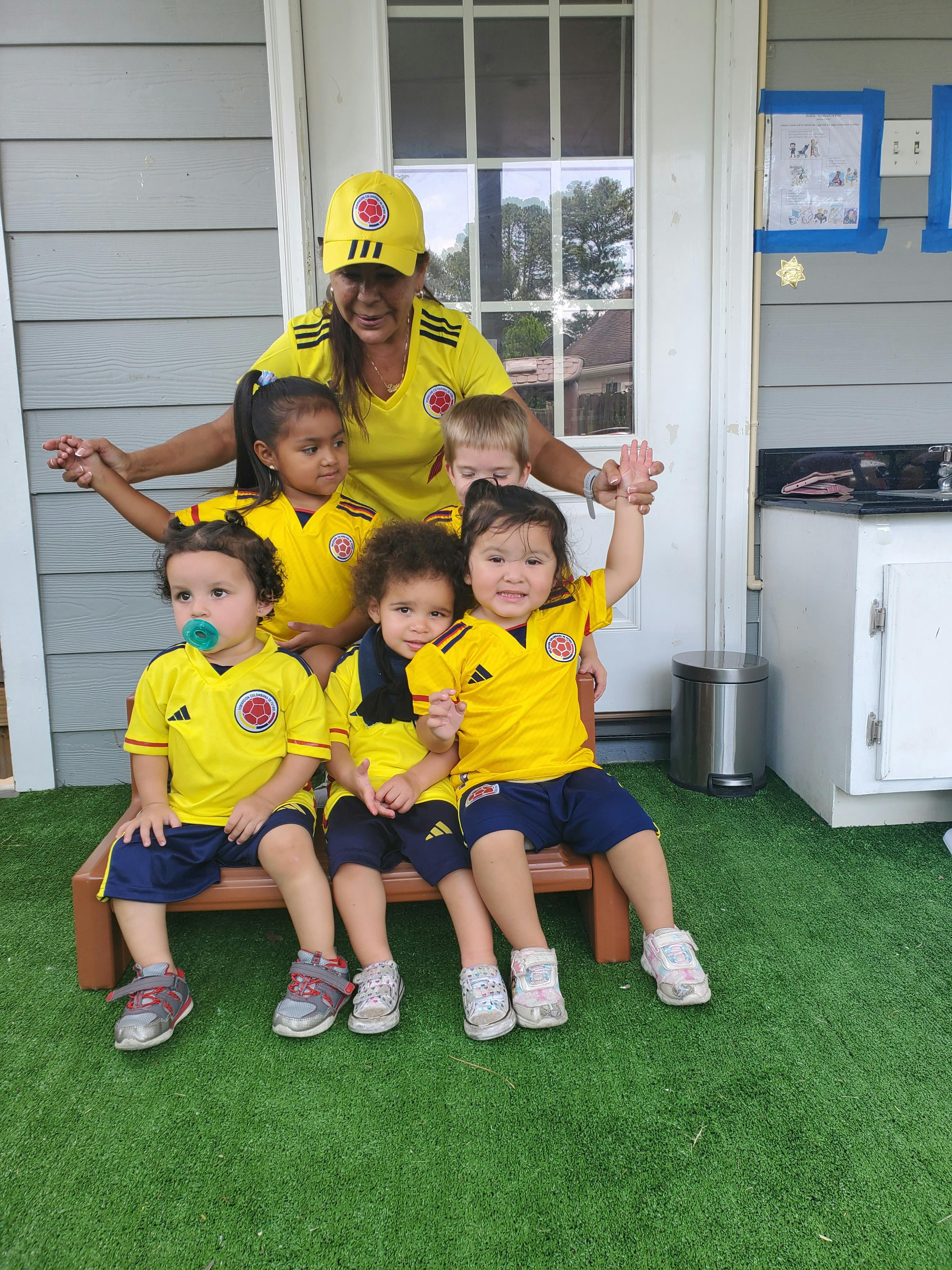 Adult and multiple children in yellow shirts and blue shorts