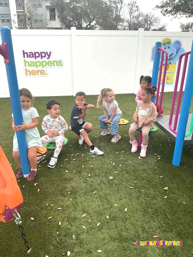 Children playing on a playground with a sign that says "happy happens here"