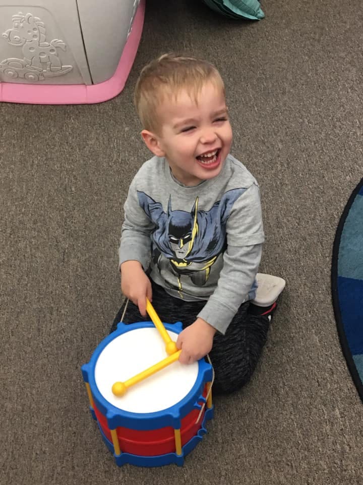 Child playing a toy drum with drumsticks