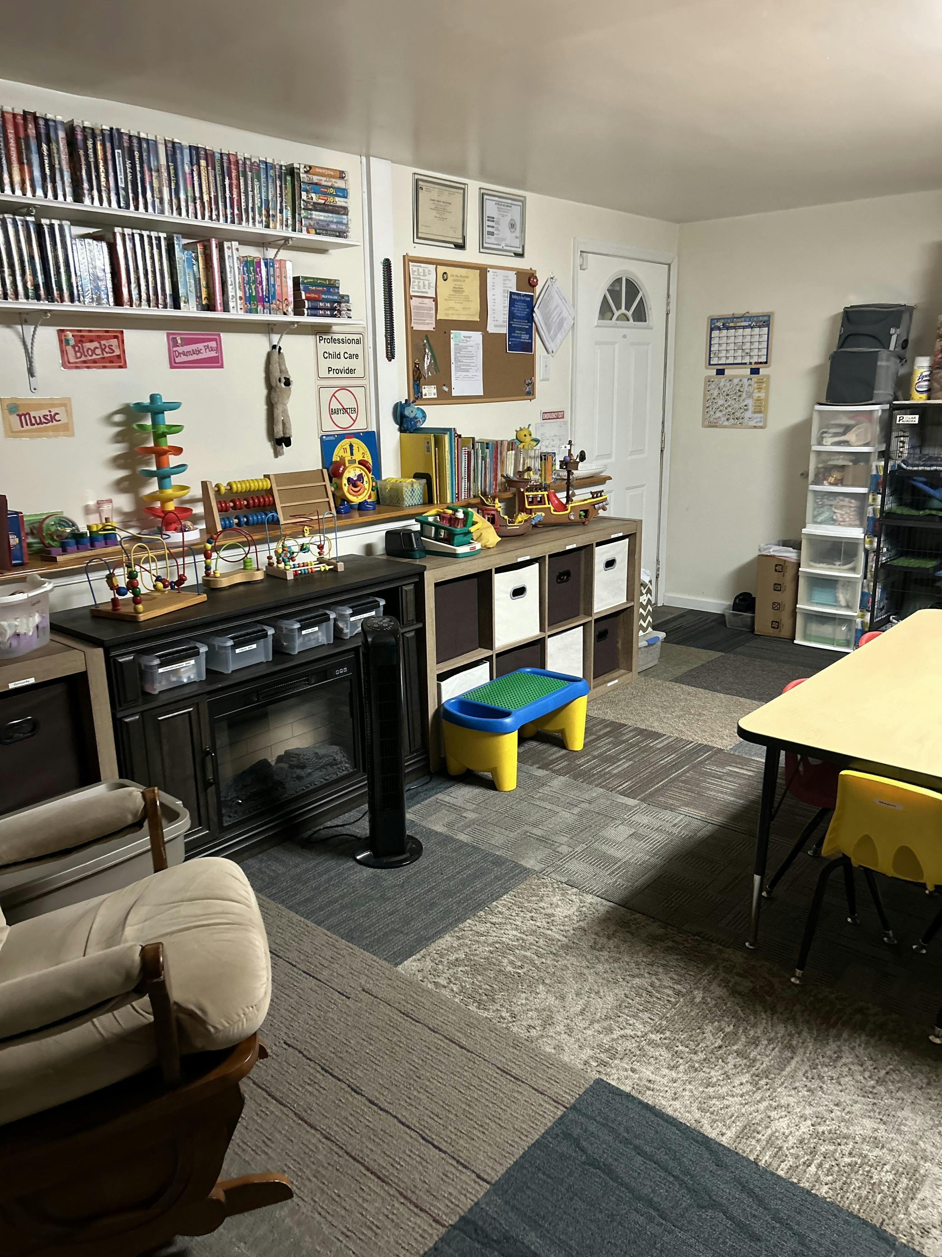 Childcare playroom with toys, activity tables, and shelving