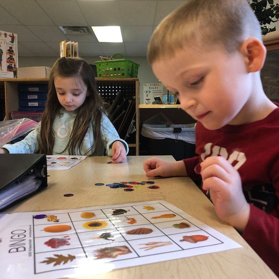 Two children playing bingo in a classroom