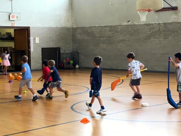 Children playing floor hockey in a gymnasium