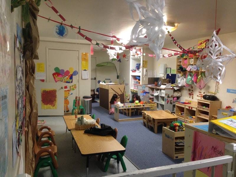 Child playing in a classroom with tables and chairs
