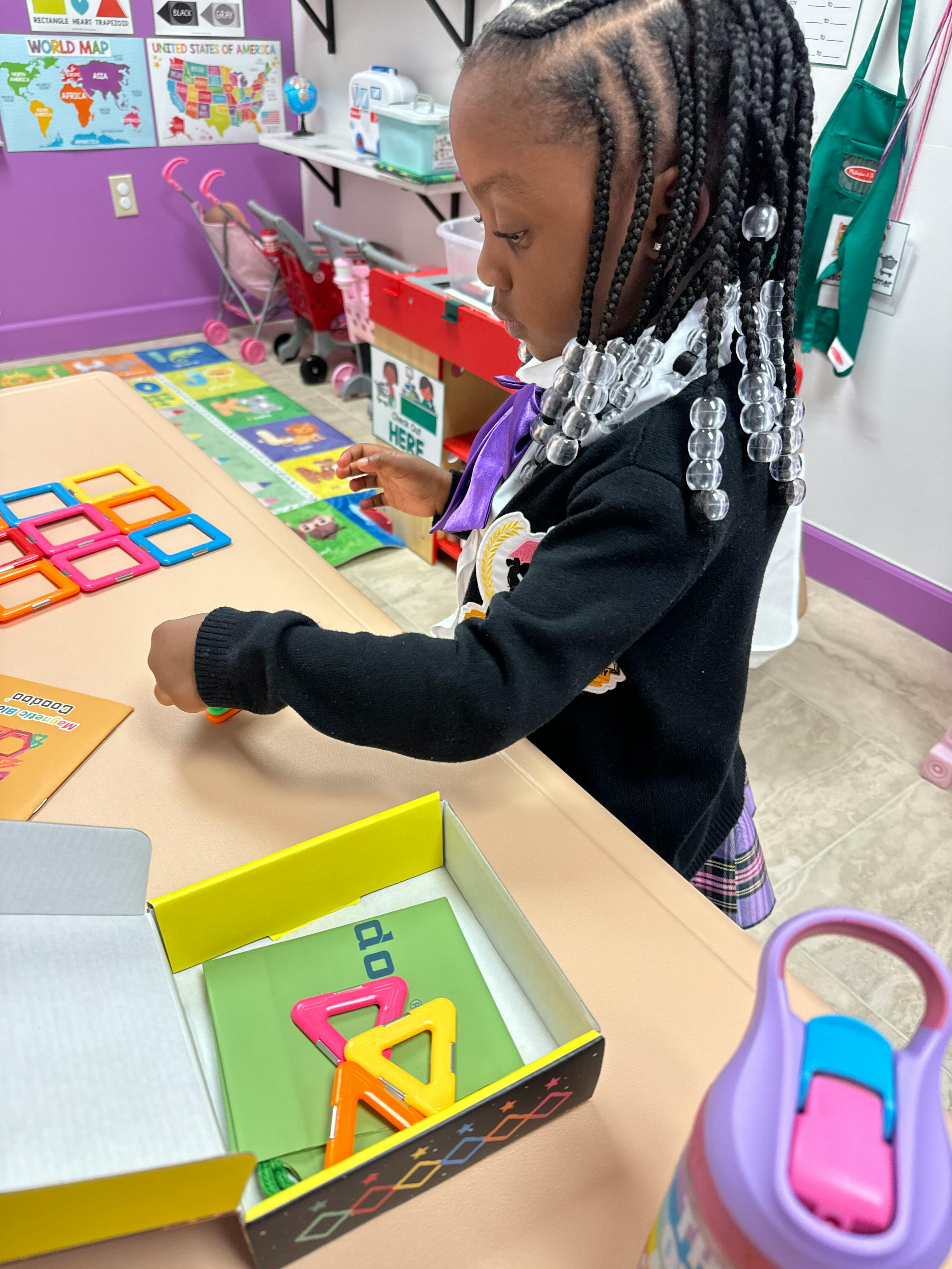 Child playing with colorful magnetic tiles at a table
