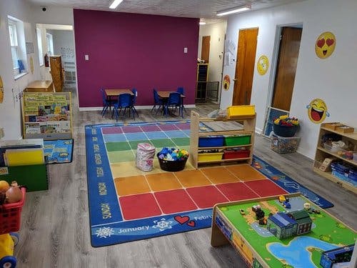 Playroom with colorful rug, small tables, and toys