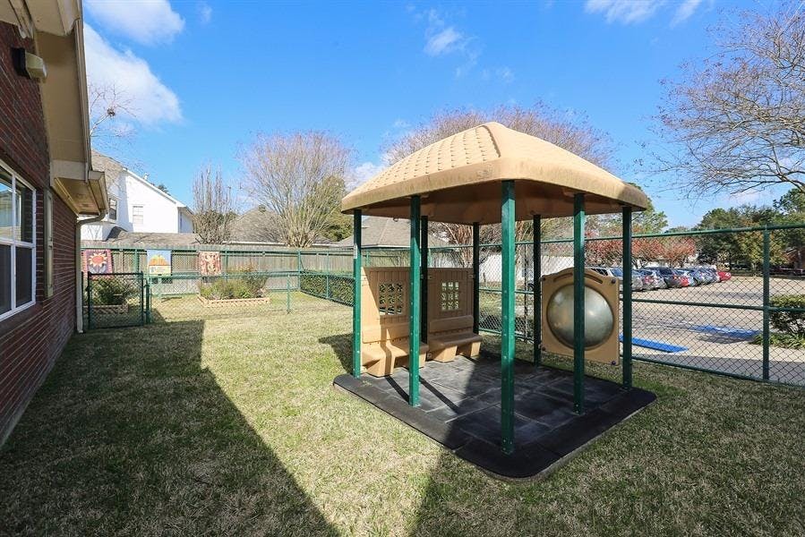 Outdoor play structure with a roof and benches on grass