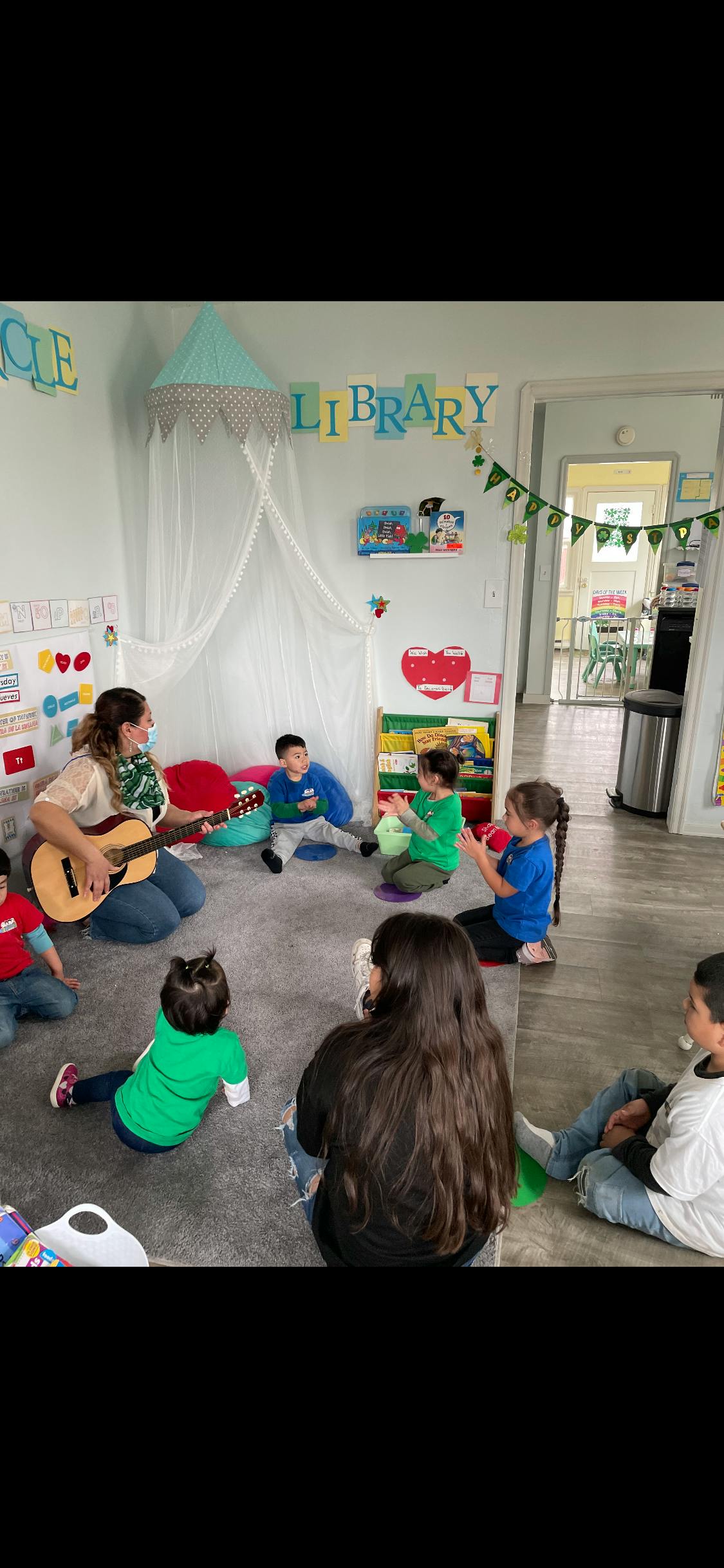 Adult playing guitar for children sitting on the floor in a classroom
