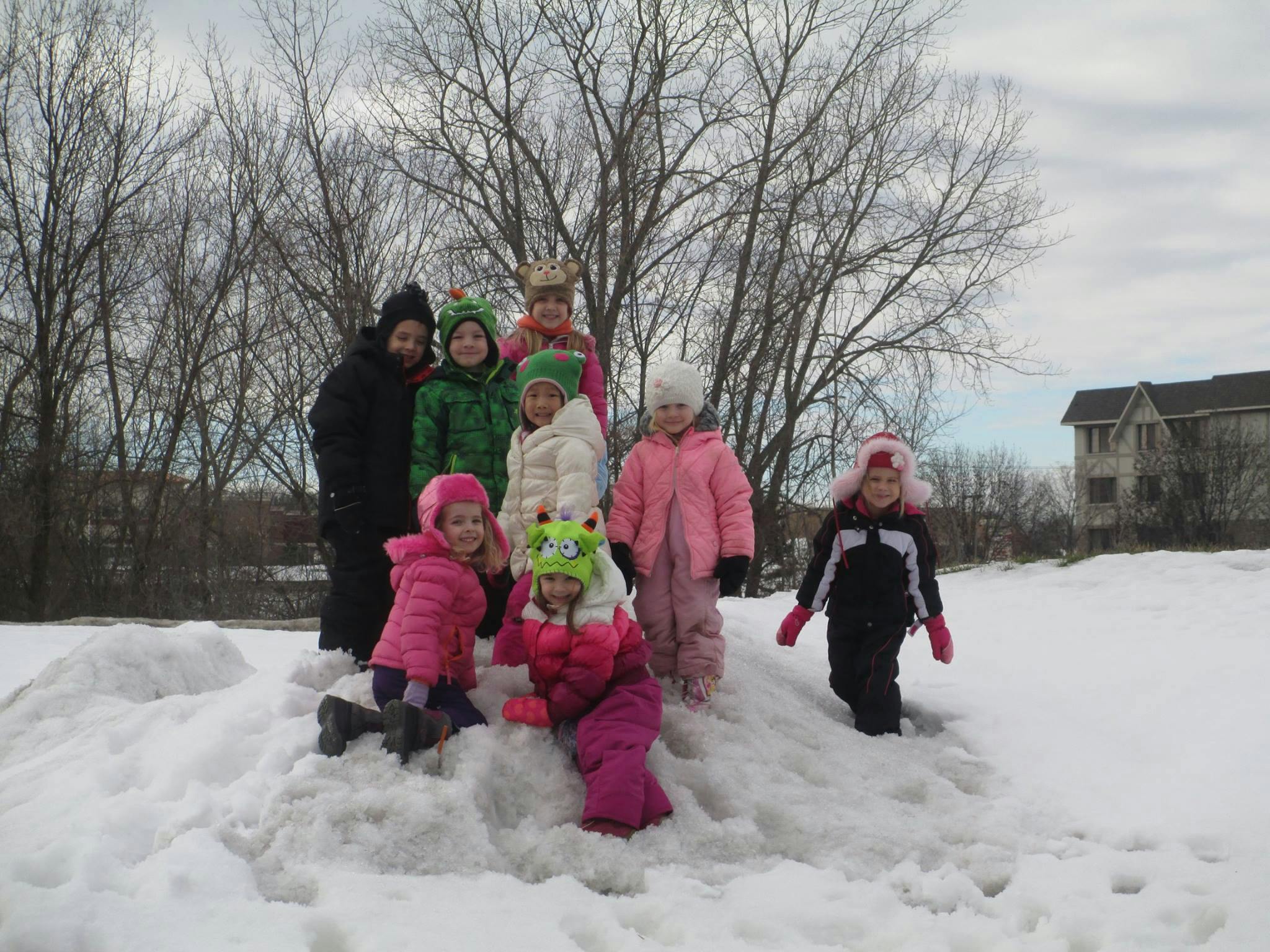 Group of children and one adult standing on a snow pile