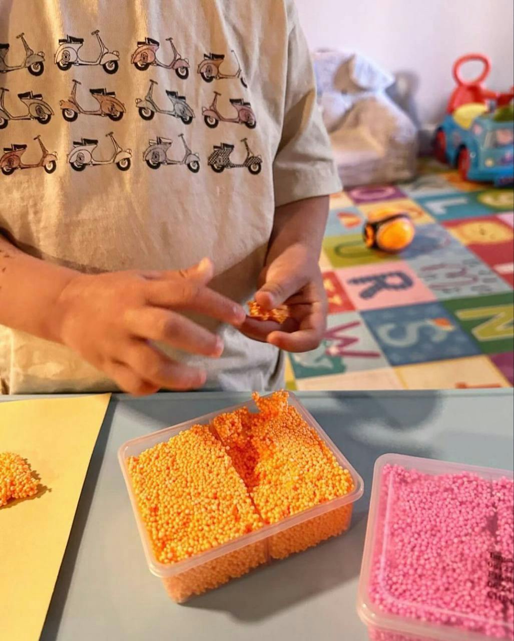 Child playing with orange foam beads