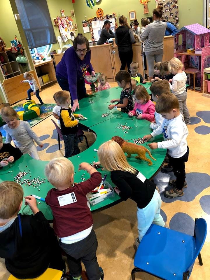 Adult and children gathered around a green table in a classroom
