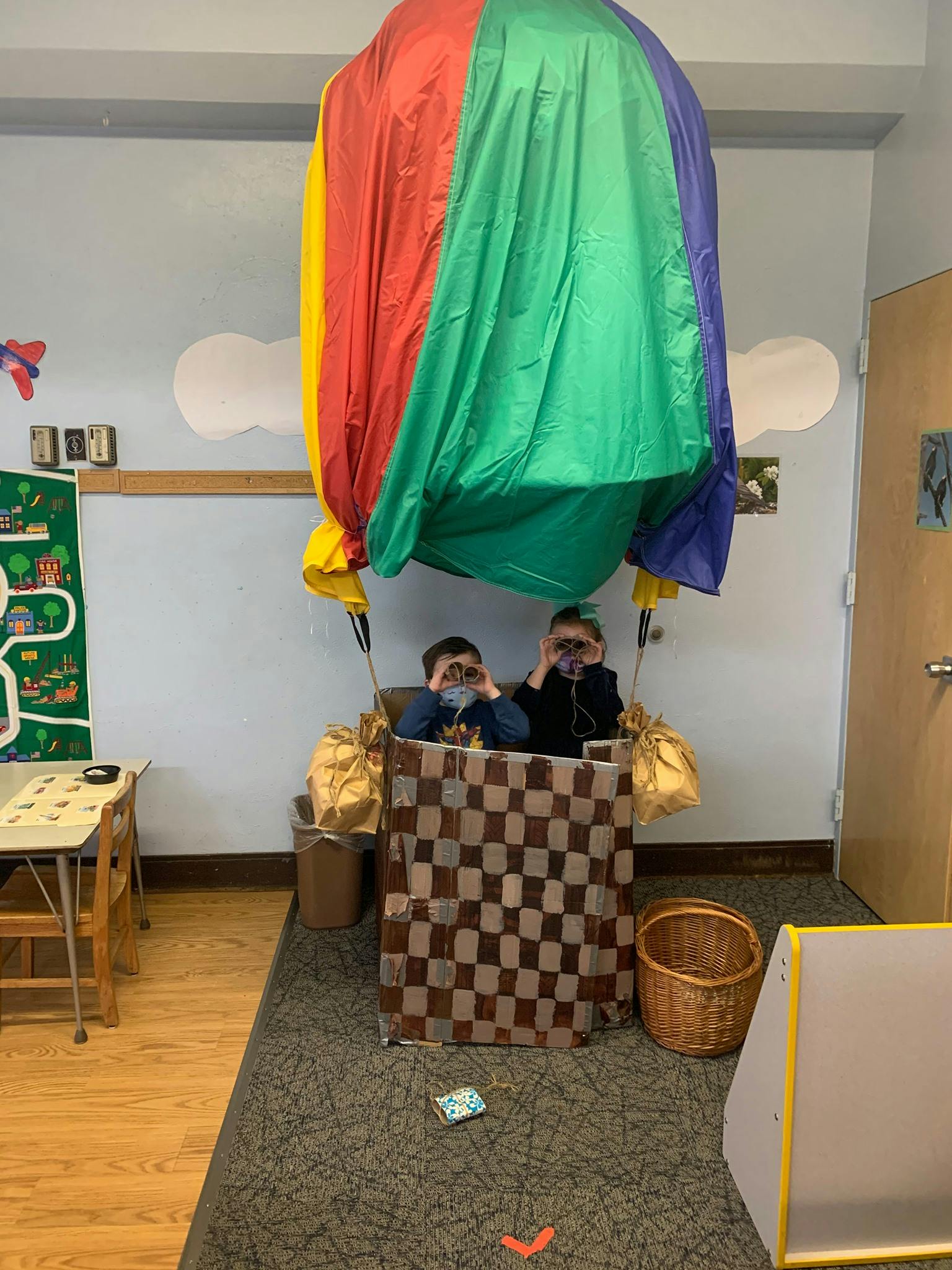 Two children in a hot air balloon prop looking through binoculars
