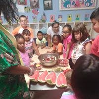 Adult and children around a table with fruit