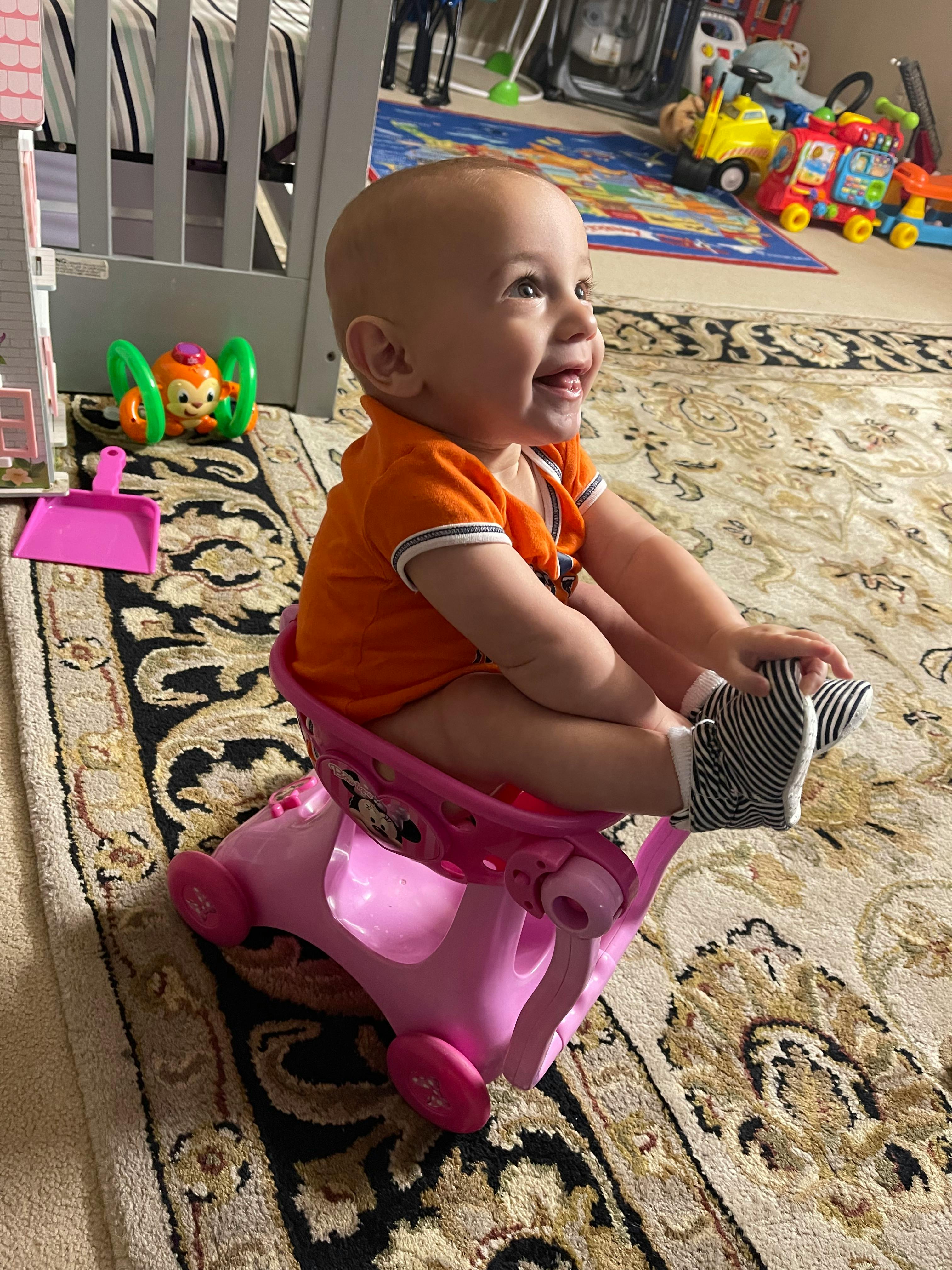 Child sitting in a pink toy car