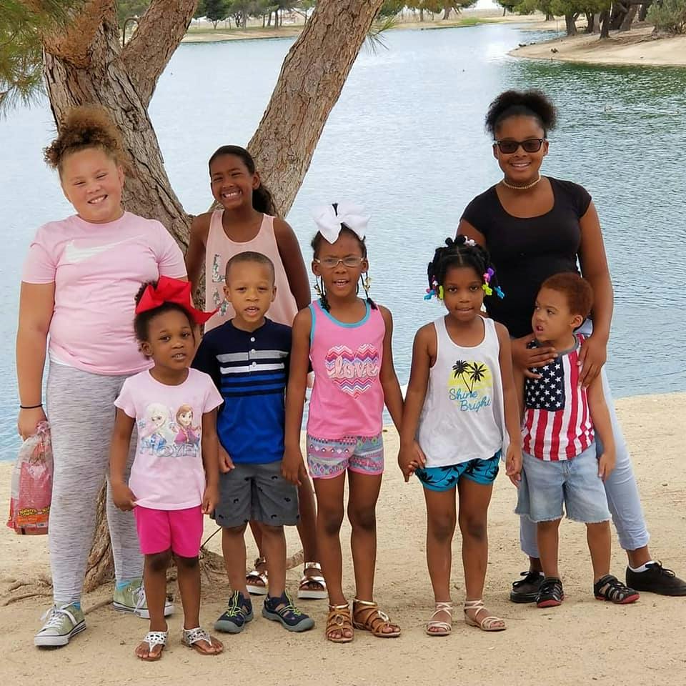 Group of children and adults standing on a beach near water