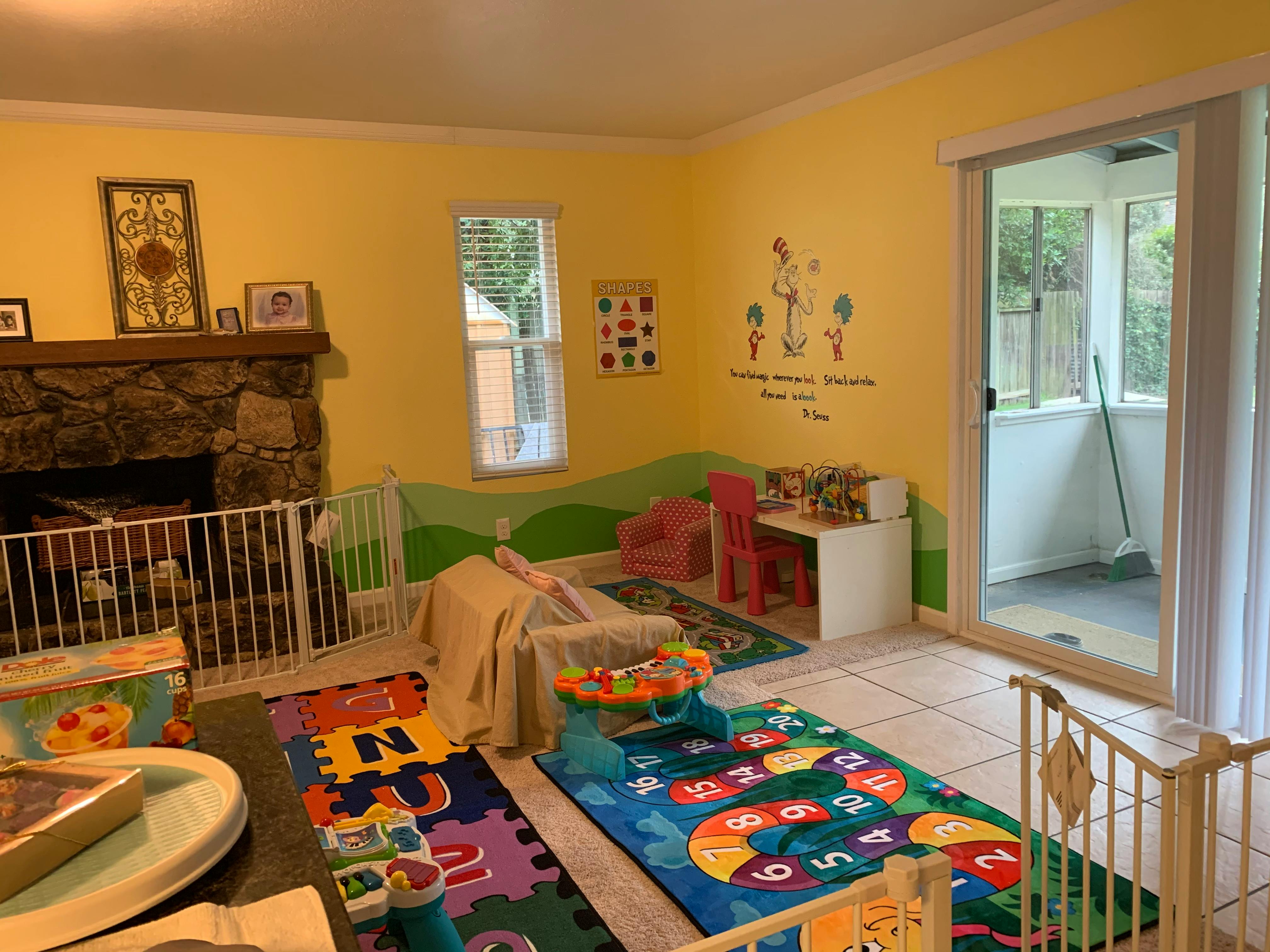 Playroom with fireplace, baby gate, and colorful play mats