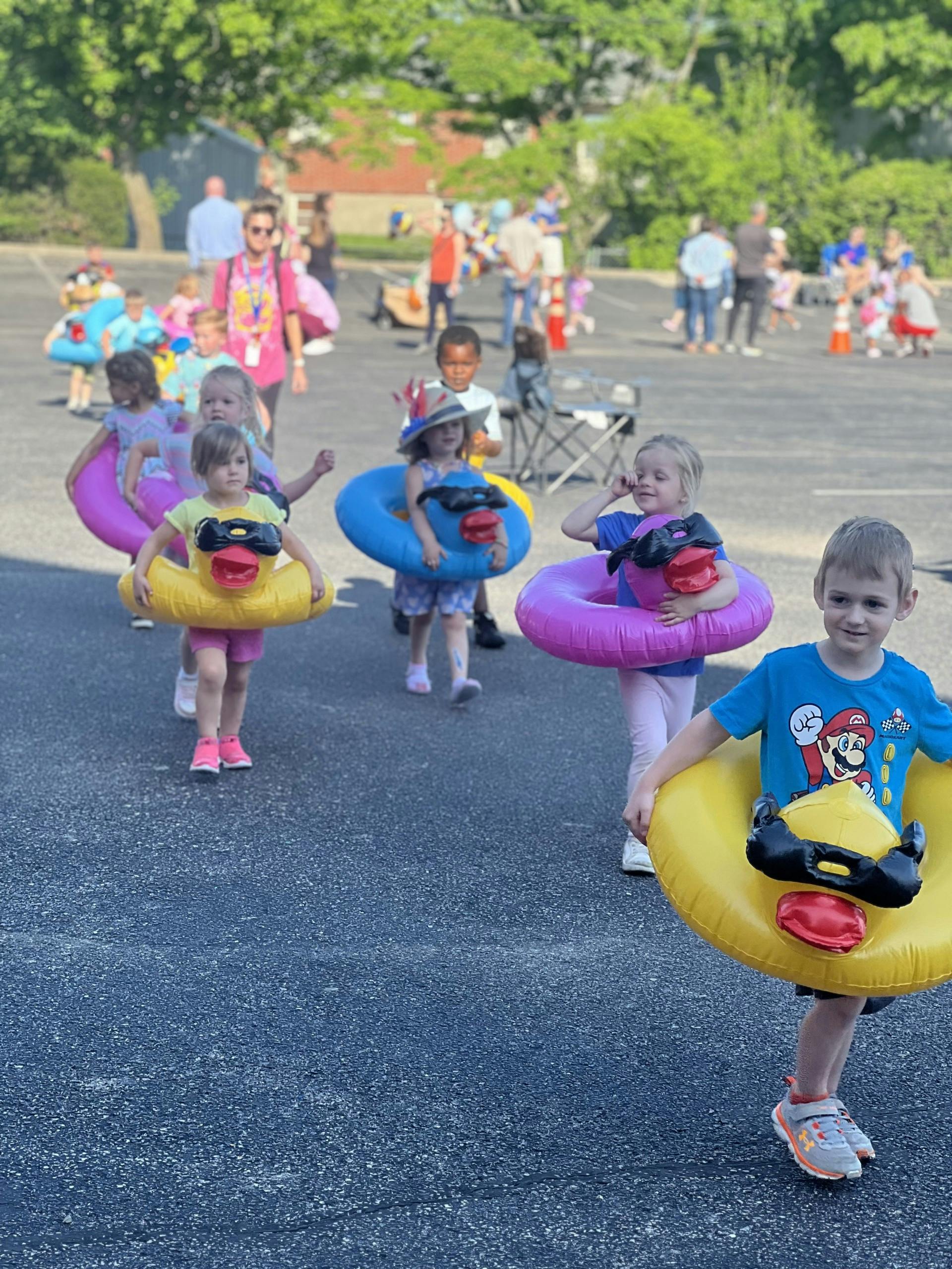 Children wearing inflatable duck and ring costumes walking outdoors
