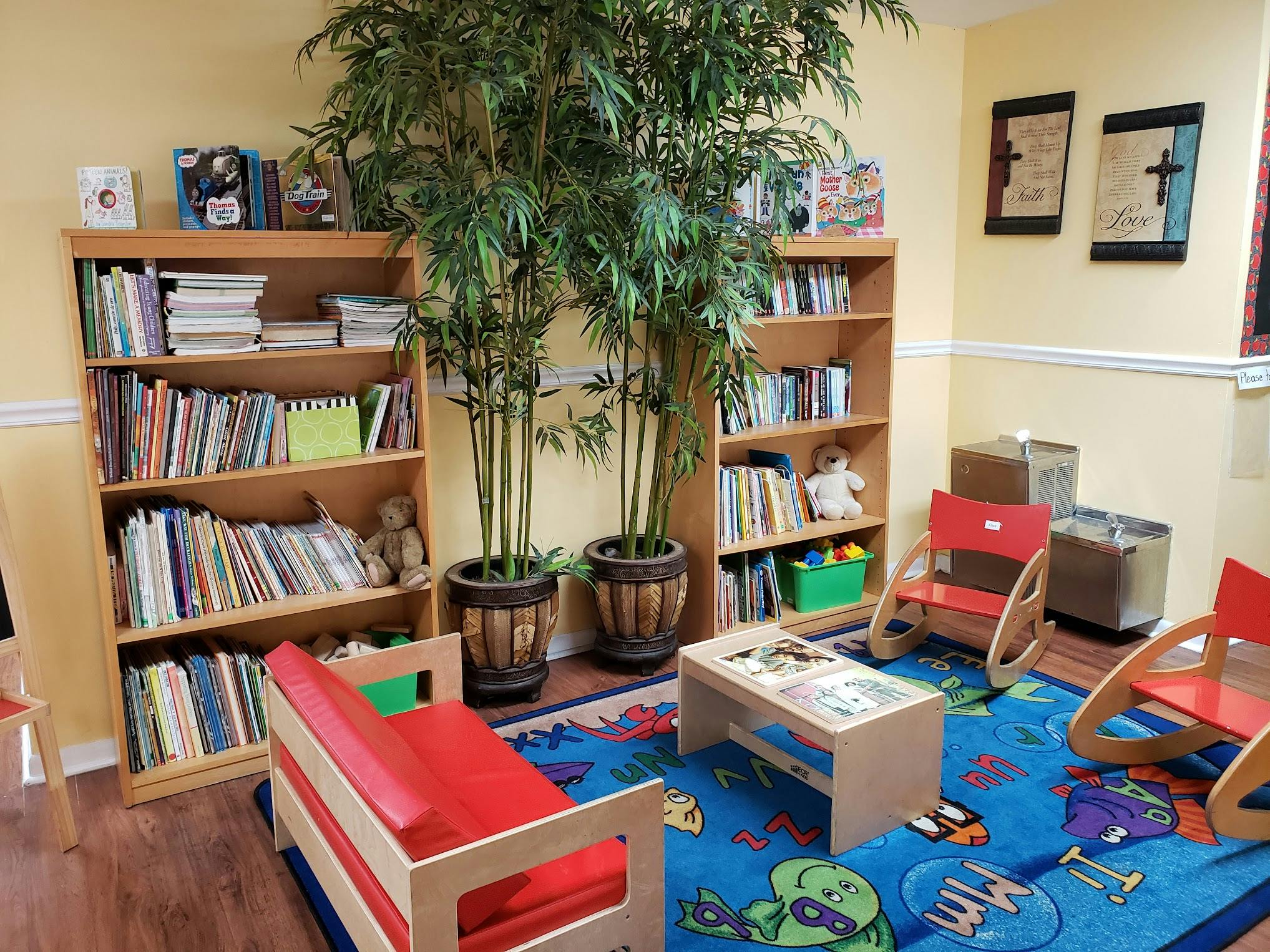 Children's reading nook with bookshelves, small chairs, and a play rug