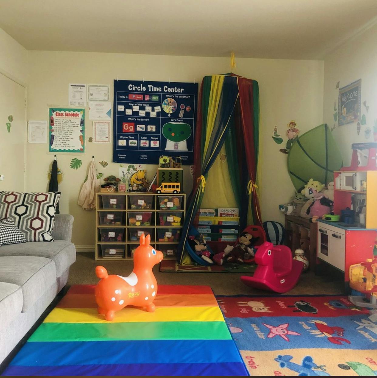 Playroom with a rainbow rug, toy storage, and a colorful tent