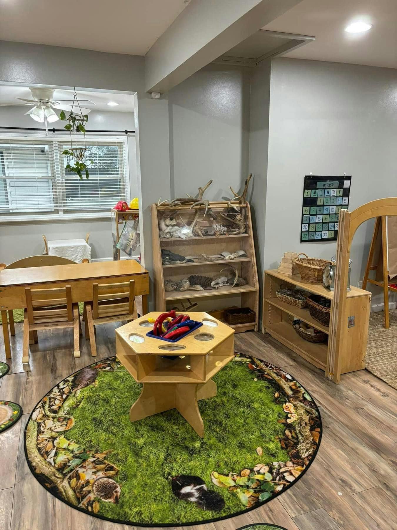 Classroom with small tables and chairs, shelves, and a round rug