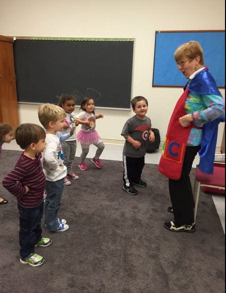 Adult in cape with children in a classroom