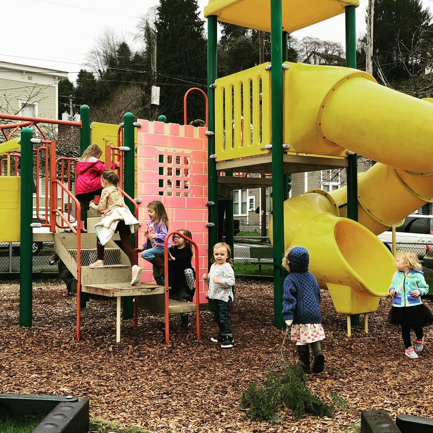 Children playing on a playground structure with slides and stairs