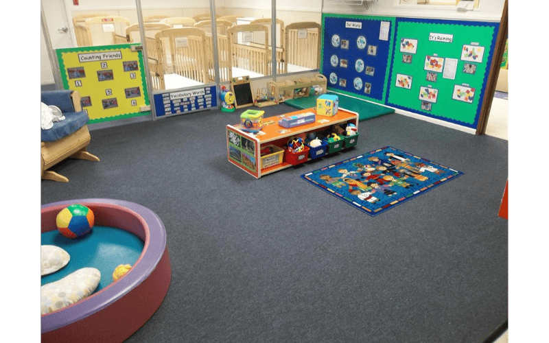 Children's classroom with cribs in background, toys, and educational posters