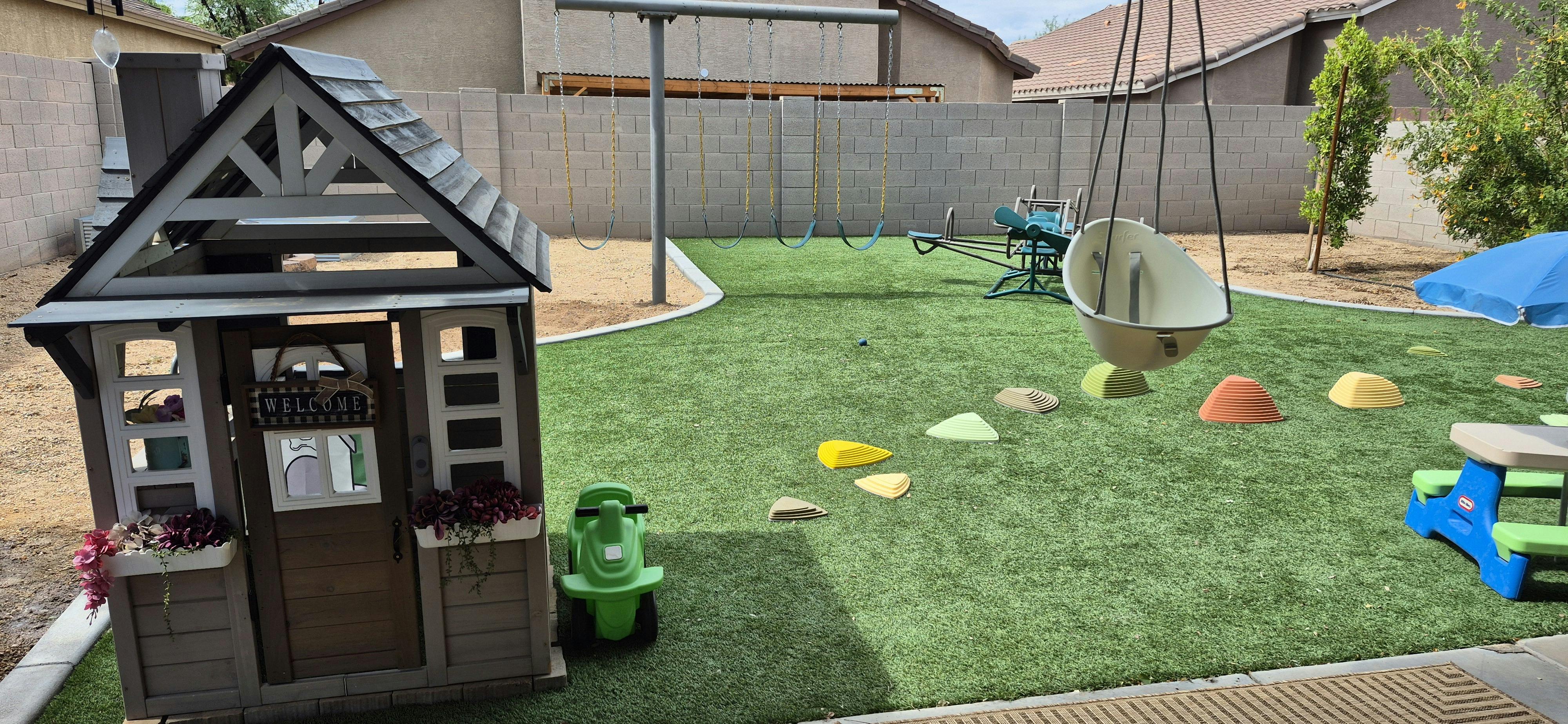 Backyard playground with playhouse, swings, and balancing stepping stones