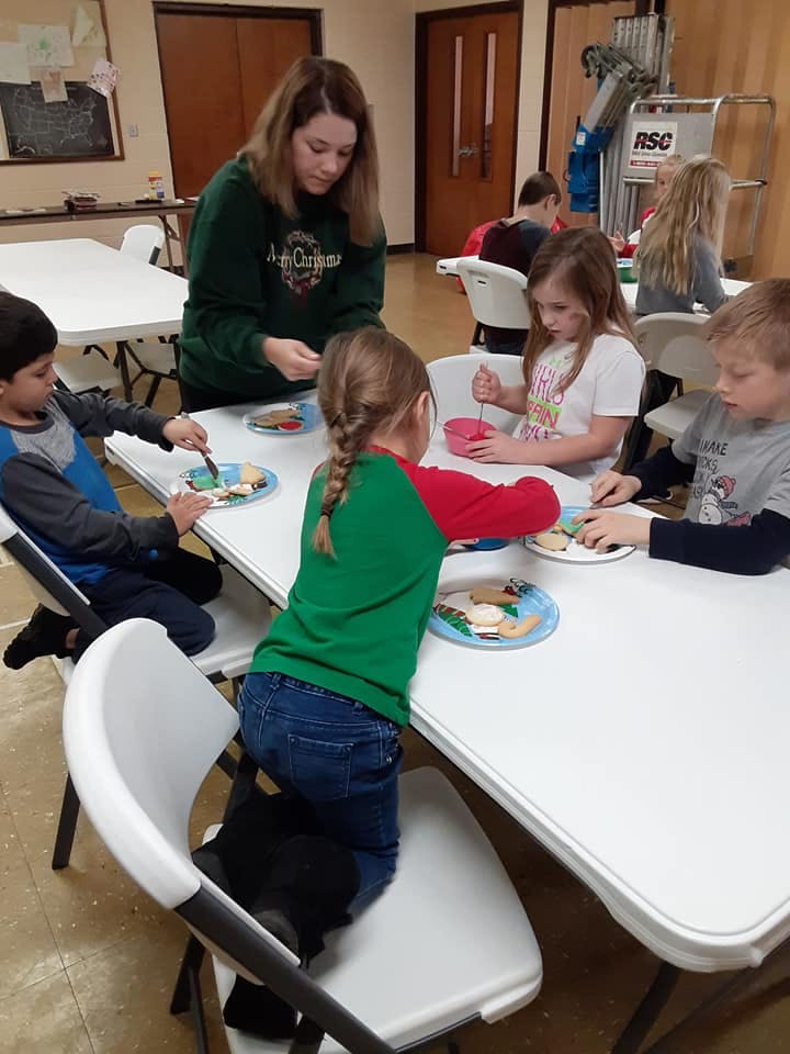 Adult and children decorating cookies at a table