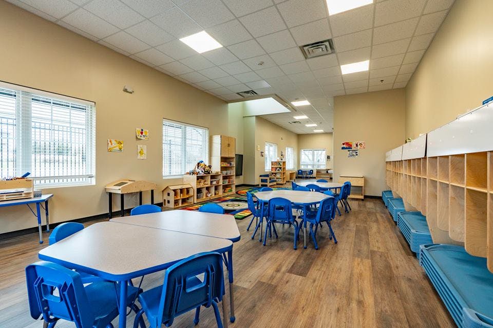 Classroom with small tables and chairs, cubbies, and windows