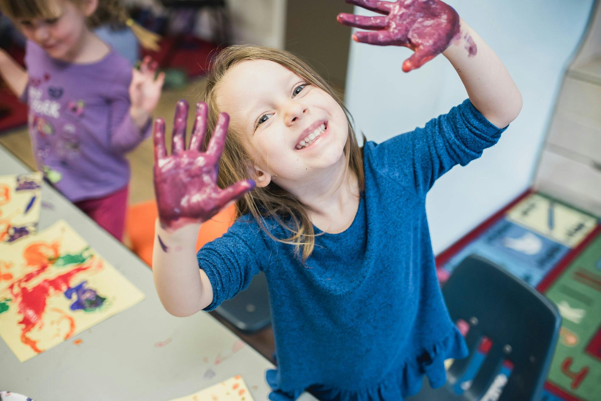 Child with paint on hands in a classroom