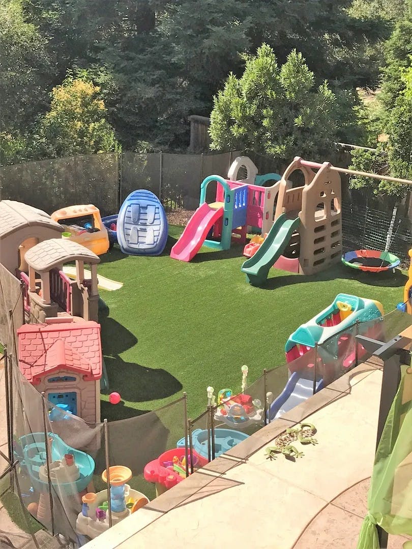 Outdoor play area with multiple plastic slides, playhouses, and water tables