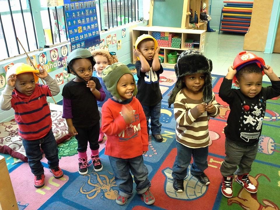 Group of children wearing various hats in a classroom