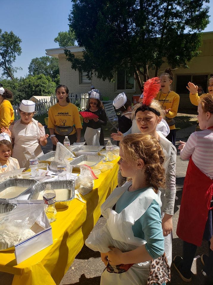 Children and teens gathered around a table with food containers