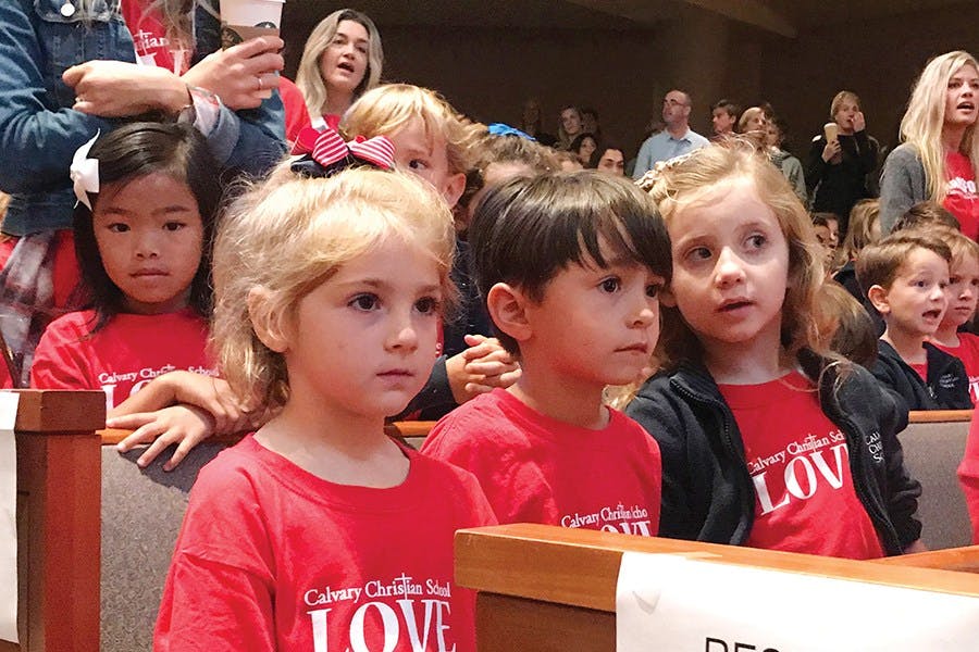 Children in red shirts sitting in an audience