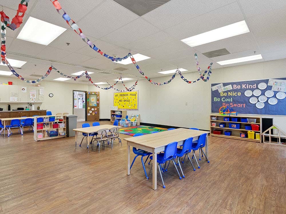 Empty classroom with tables, chairs, and colorful decorations