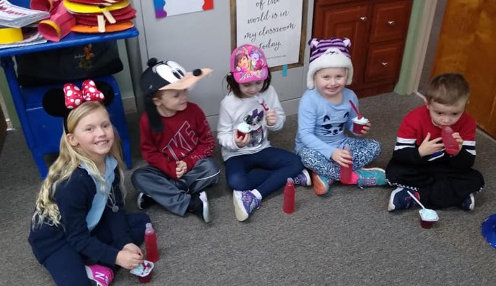 Five children sitting on the floor with drinks