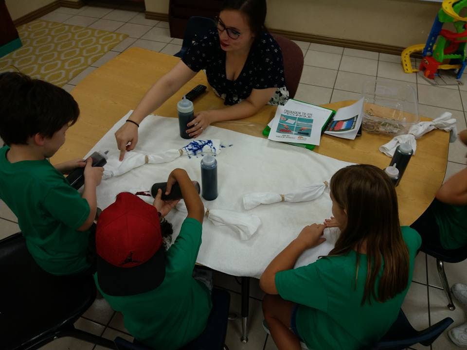 Adult and children at a table tie-dyeing fabric