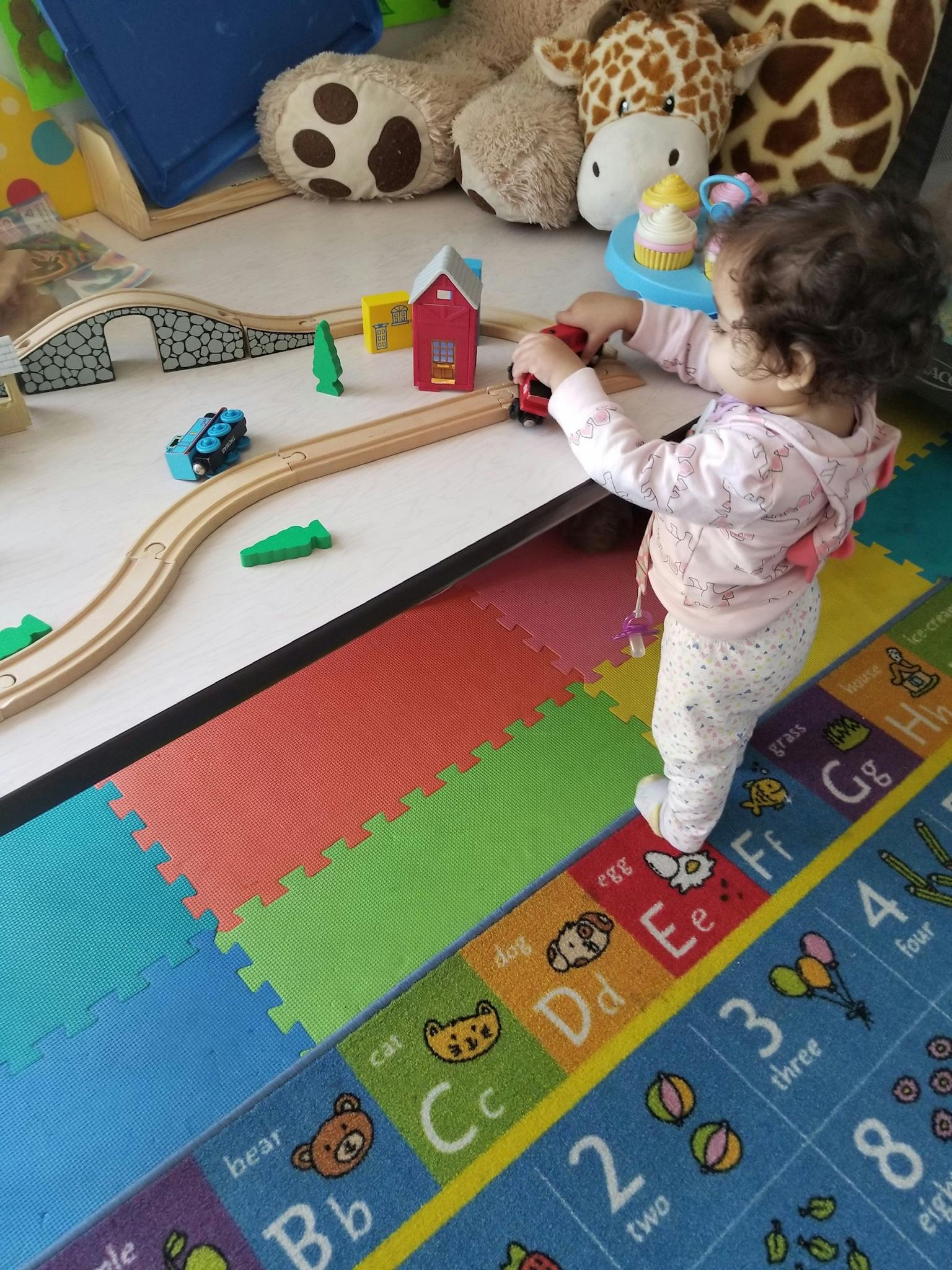 Child playing with a toy train on a wooden track